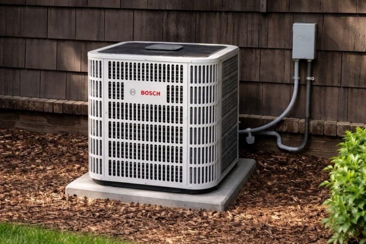 This image shows an outdoor air conditioning condenser unit installed as part of AC Installation and Replacement in Burbank CA. The unit is placed on a base next to a residential home with wood siding and mulch ground cover. Electrical conduit and a disconnect box are visible, which are key parts of a proper installation setup. The system appears clean and newly installed, which reflects a typical replacement project for homeowners in Burbank. Green Planet HVAC provides AC installation and replacement services in Burbank CA, helping homeowners upgrade their cooling systems and improve indoor comfort. Call (818) 383-6516 to schedule service.