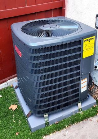 Modern outdoor heat pump system used for emergency heat pump repair in North Hollywood, CA by Green Planet HVAC. The unit sits on a secure base next to a residential wall and fence, with visible ventilation panels and top fan housing in good condition. The system reflects a typical setup that may require repair service during system failure or cooling issues. Green Planet HVAC provides emergency heat pump repair in North Hollywood, CA, offering fast service and reliable solutions. Call (818) 383-6516 for immediate repair support and HVAC service.